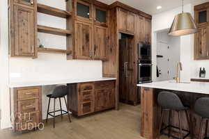 Kitchen with a breakfast bar, sink, decorative light fixtures, light hardwood / wood-style flooring, and stainless steel microwave