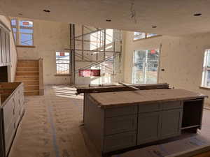 Kitchen featuring a textured ceiling, gray cabinets, light stone counters, and plenty of natural light