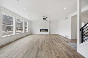 Unfurnished living room with ceiling fan and light hardwood / wood-style flooring