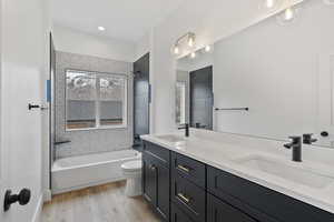 Full bathroom featuring vanity, hardwood / wood-style flooring, tiled shower / bath combo, and toilet