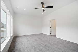 Empty room featuring ceiling fan, lofted ceiling, carpet flooring, and a wealth of natural light