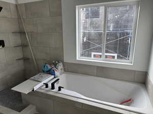 Bathroom with a wealth of natural light and a relaxing tiled tub