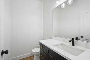 Bathroom featuring vanity, hardwood / wood-style floors, and toilet