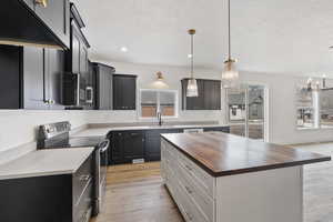 Kitchen with stainless steel appliances, sink, butcher block countertops, a kitchen island, and a healthy amount of sunlight