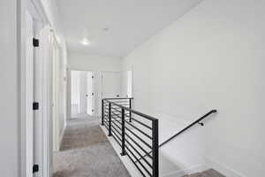 Hallway featuring light colored carpet