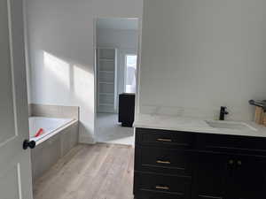 Bathroom featuring vanity, hardwood / wood-style flooring, and tiled tub