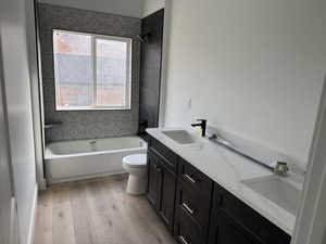 Full bathroom featuring hardwood / wood-style flooring, vanity, toilet, and tiled shower / bath