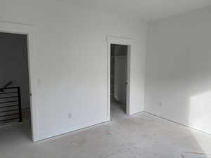 Unfurnished bedroom featuring a walk in closet and a closet