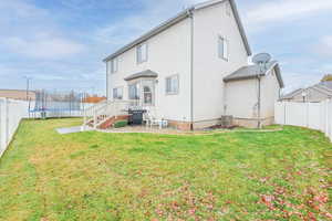 Rear view of property featuring a lawn and a trampoline