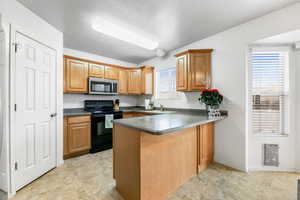 Kitchen featuring sink, kitchen peninsula, a textured ceiling, and black electric range