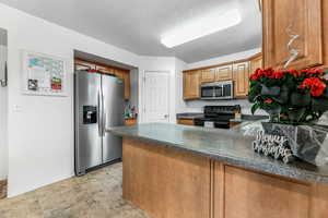 Kitchen featuring kitchen peninsula, stainless steel appliances, and a textured ceiling