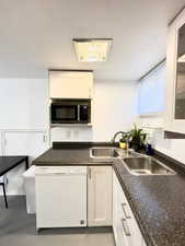 Kitchen with white cabinets, dishwasher, and sink