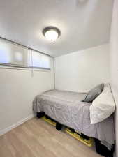 Bedroom with hardwood / wood-style floors and a textured ceiling