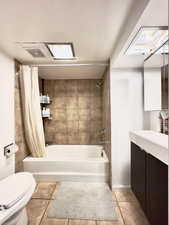 Full bathroom with tile patterned floors, shower / tub combo with curtain, vanity, and toilet