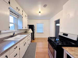 Kitchen featuring sink, white cabinetry, stainless steel appliances, and light hardwood / wood-style flooring