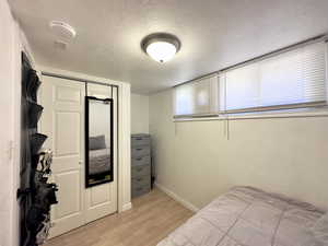 Bedroom with a closet, light hardwood / wood-style floors, and a textured ceiling