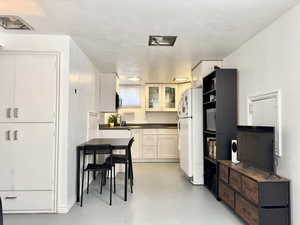 Kitchen with white cabinetry, white fridge, and a textured ceiling