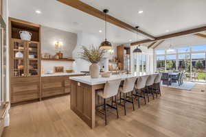 Kitchen featuring pendant lighting, a large island, a breakfast bar area, backsplash