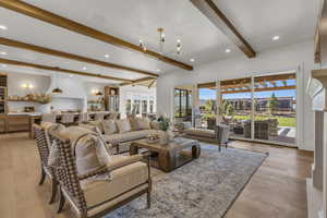 Living room featuring a notable chandelier, beam ceiling, and light wood-type flooring