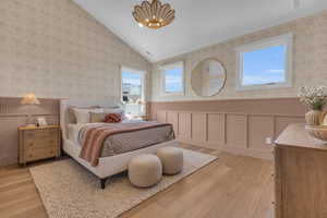 Themed Bedroom with lofted ceiling, a notable chandelier, and light wood-type flooring