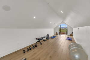 Exercise area above ADU garage featuring vaulted ceiling and light hardwood / wood-style floors