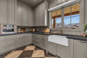 Kitchen pantry featuring gray cabinets, tasteful backsplash, sink, and oven