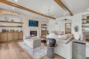 Living room featuring built in shelves, light wood-type flooring, and beamed ceiling