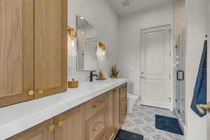 ADU Bathroom with a shower with door, vanity, tile patterned flooring, and toilet