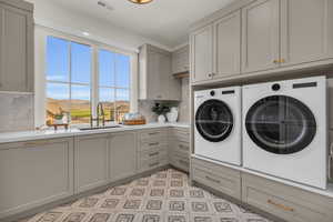 Clothes washing area with a mountain view, sink, washing machine and dryer, and cabinets