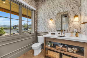 Powder Bathroom featuring wood-type flooring, vanity, and toilet