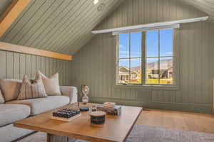 Living room featuring lofted ceiling, hardwood / wood-style floors, and wood walls