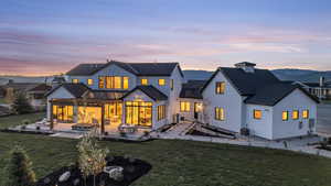 Back house at dusk featuring a patio, a mountain view, a yard, and central AC unit