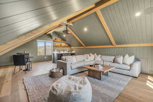 Theater with lofted ceiling with beams and light wood-type flooring