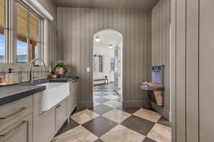 Kitchen pantry featuring white cabinetry, sink, and wooden walls