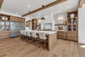 Kitchen with built in fridge, a spacious island, a kitchen bar, hanging light fixtures, and white oak flooring