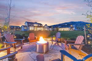 Patio terrace at dusk with a mountain view, a fire pit, and a lawn