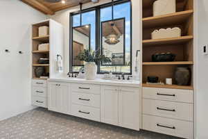 Bar with sink, a wealth of natural light, and white cabinets