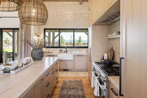 Kitchen with sink, white oak  flooring, light brown cabinets, light stone countertops, and range with two ovens