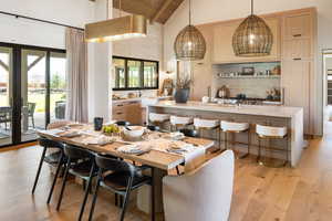 Dining area with beam ceiling, high vaulted ceiling, light hardwood / wood-style floors, wooden ceiling, and french doors