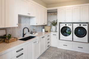 Laundry room featuring cabinets, sink, and washing machine and clothes dryer