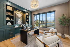 Office space with light hardwood / wood-style floors and a notable chandelier