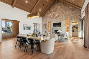 Dining area featuring french doors, a large fireplace, wood ceiling, beam ceiling, and light hardwood / wood-style flooring