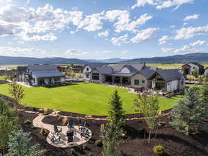 Rear view of property featuring a patio, a mountain view, a yard, and a fire pit