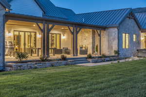 Back of house featuring a yard, a patio, and an outdoor stone fireplace