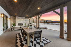 Snow covered patio with a mountain view and an outdoor stone fireplace