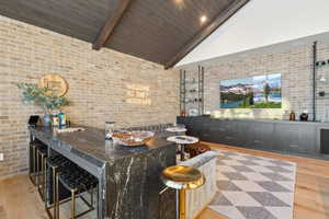 Bar with brick wall, vaulted ceiling with beams,  and dark stone counters