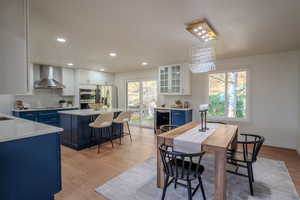 Dining area with beverage cooler, light wood-type flooring, a wealth of natural light, and an inviting chandelier