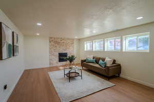 Living room with a stone fireplace, plenty of natural light, and light wood-type flooring