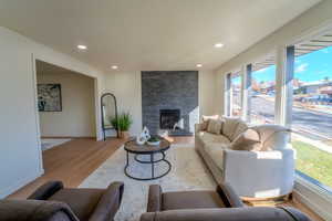 Living room with light wood-type flooring and a stone fireplace