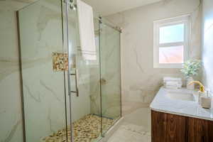 Bathroom with vanity, a shower with shower door, and tile walls